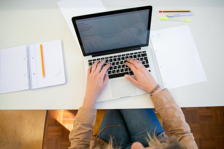 A student's hand seen at a laptop.