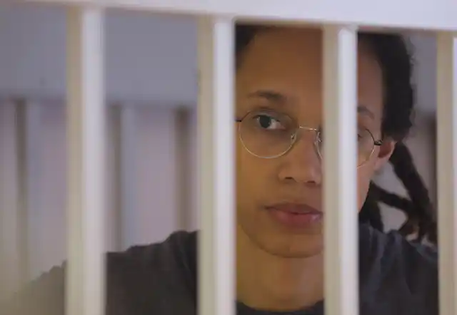 Brittney Griner, looks plaintively through white bars.