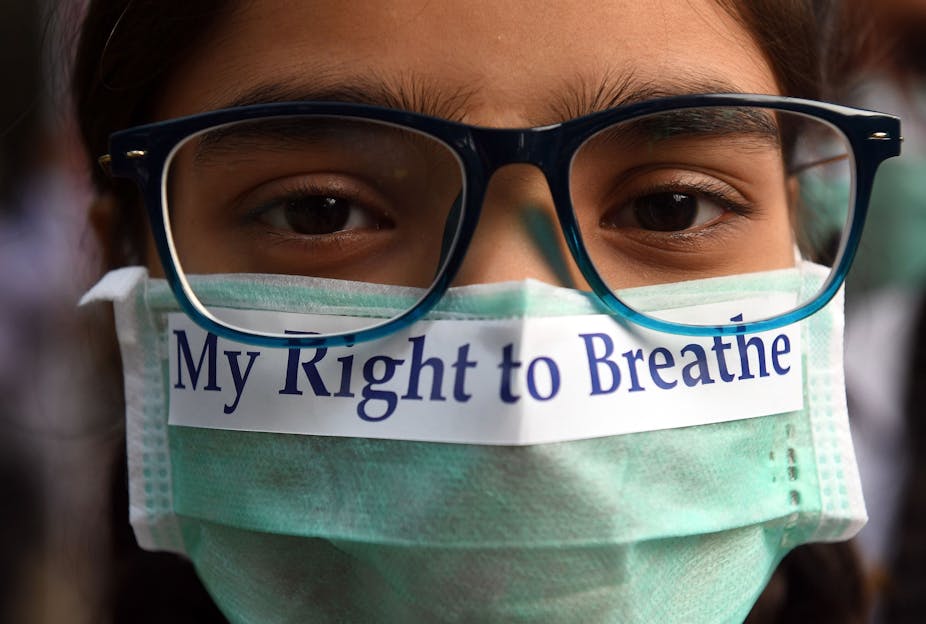 A young person in glasses wears a face mask with the printed words: "My right to breathe" on it