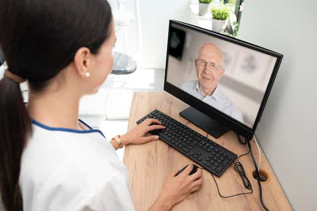 Nurse looking at computer screen image of older man