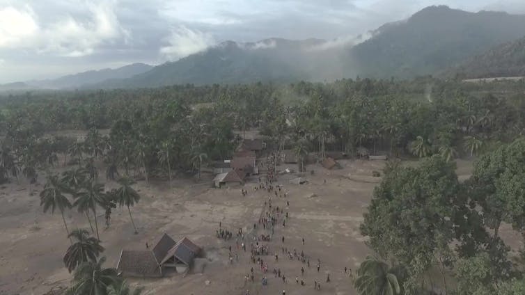 A grainy aerial shot of a small village covered by volcanic ash