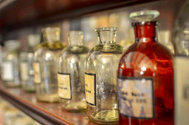 Vintage glass medicine bottles on a shelf