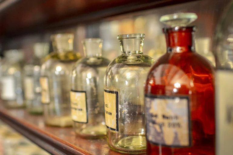 Vintage glass medicine bottles on a shelf