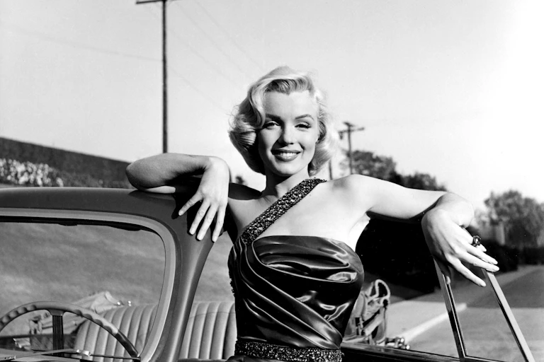 Marilyn Monroe apoyada en un coche descapotable.