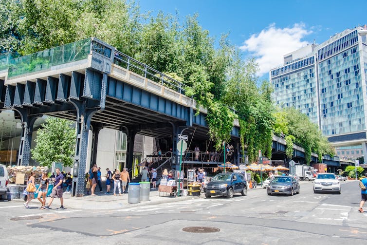 Plantlife spills over the edges of an elevated railway above a busy intersection