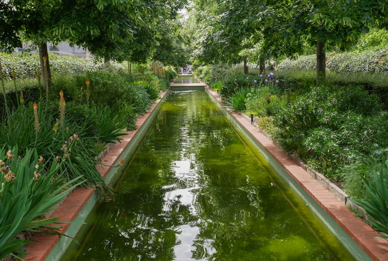 A pond set between planted beds in an elevated walkway.