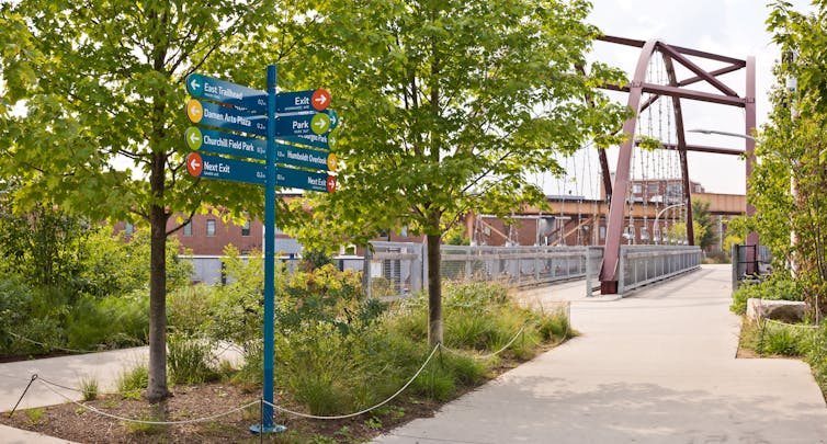 Signposts at a junction in a pedestrianised green space.