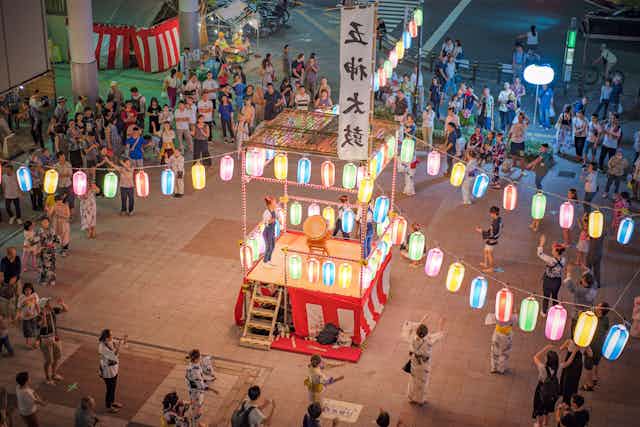 Colourful lanterns with people on a city plaza.