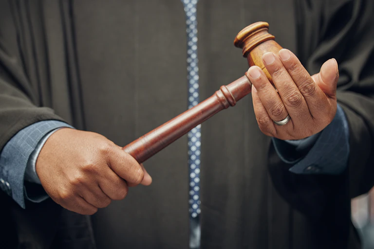 A man holding a gavel hits it against one hand