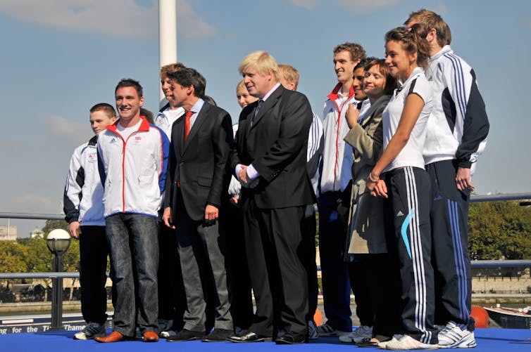 Athletes and people in suits pose for a photograph.