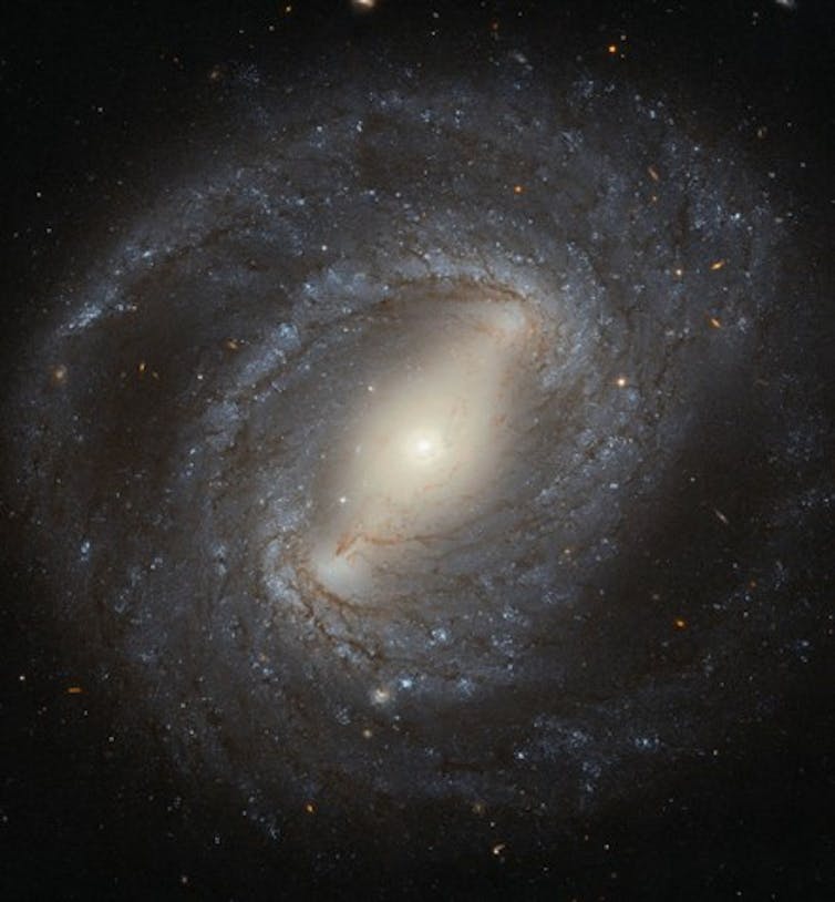 A swirling spiral of blue and white glowing stars on a dark background
