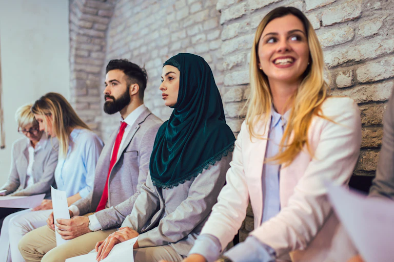 Candidates waiting for a job interview. One of the women is wearing a hijab.