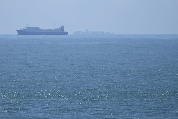 A large ship moves along a blue sea.