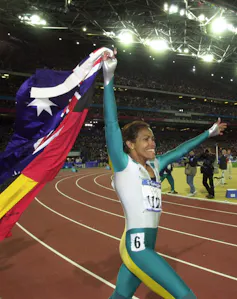 Cathy Freeman walking a lap of honour at the 2000 Sydney Olympic Games with both Aboriginal and Australian flags.