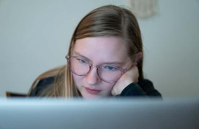 Teenage girl looking at laptop screen.