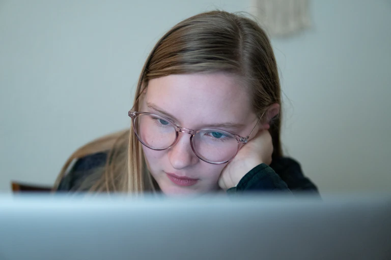Teenage girl looking at laptop screen.