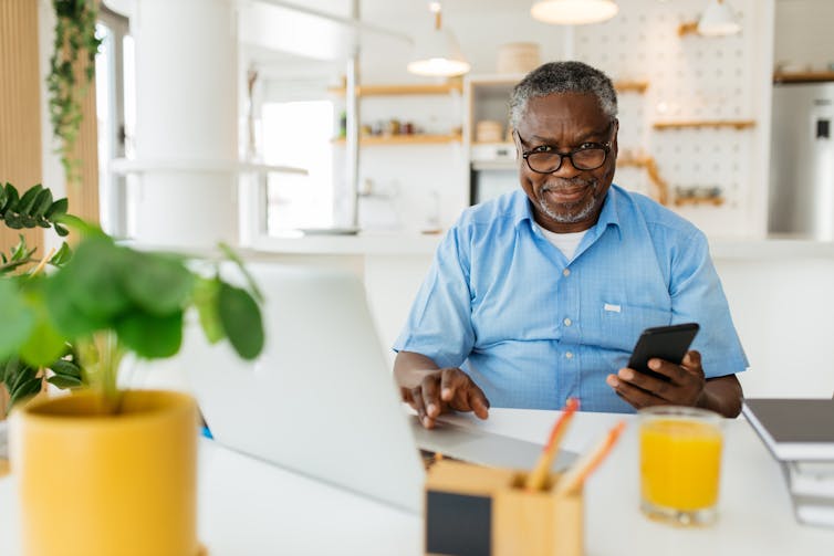 Older man at laptop with phone