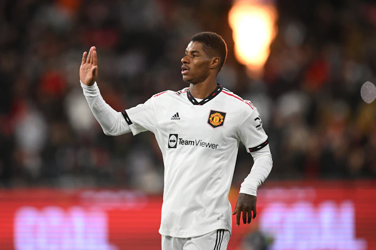 Marcus Rashford in white football kit with his hand raised for a high five