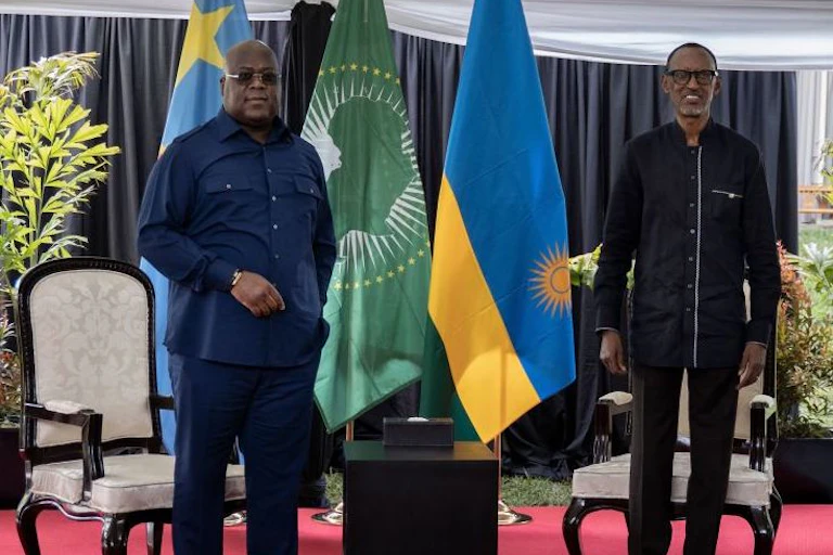 Men standing on stage with Rwanda, Congo and African Union flags behind them.