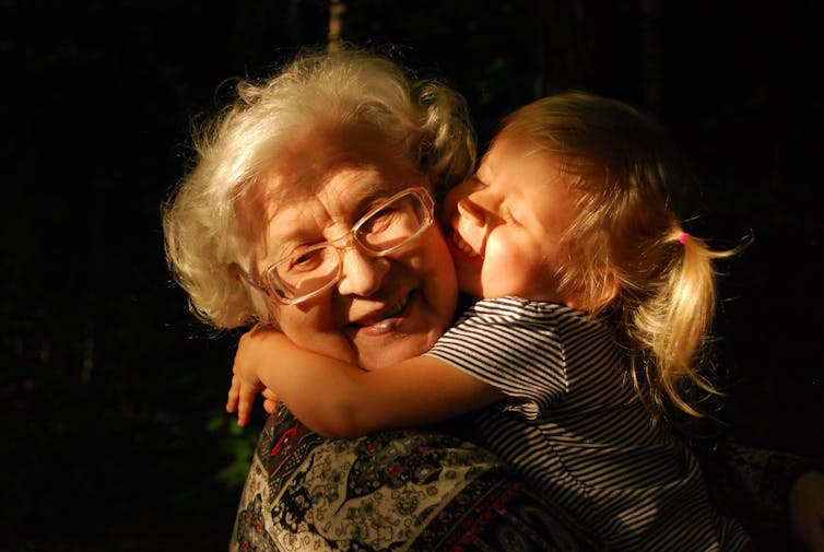 A grandmother is hugged by her granddaugher.