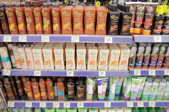 Four shelves in a ddrugstore crammed with bottles and cans of sunscreen