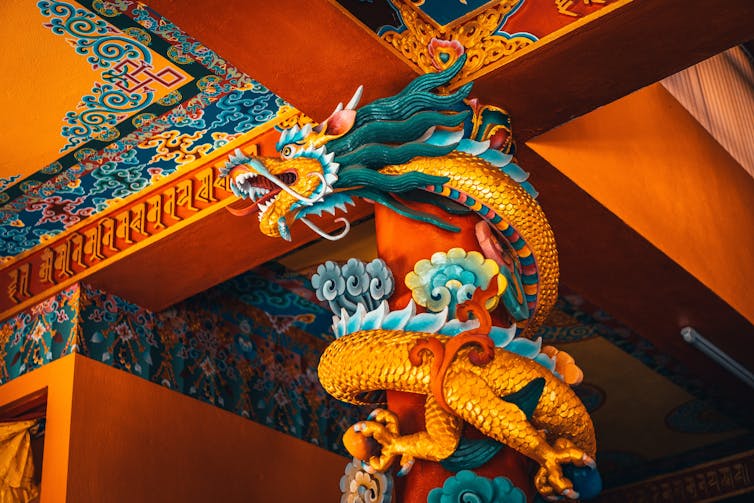 Colorful dragon wrapped around a column near the ceiling.