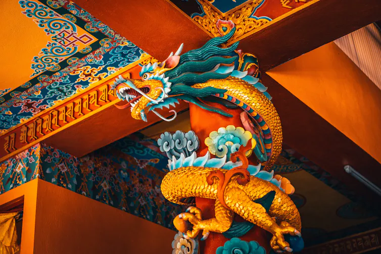 Colorful dragon wrapped around a column near the ceiling.