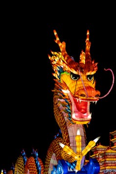 A colorful dragon sculpture lit internally against a black backdrop.