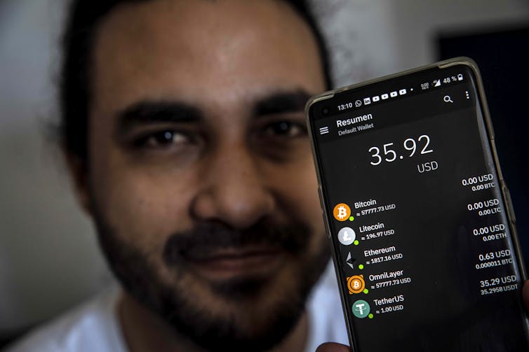 man shows the screen of his phone on which his cryptocurrency balance can be seen
