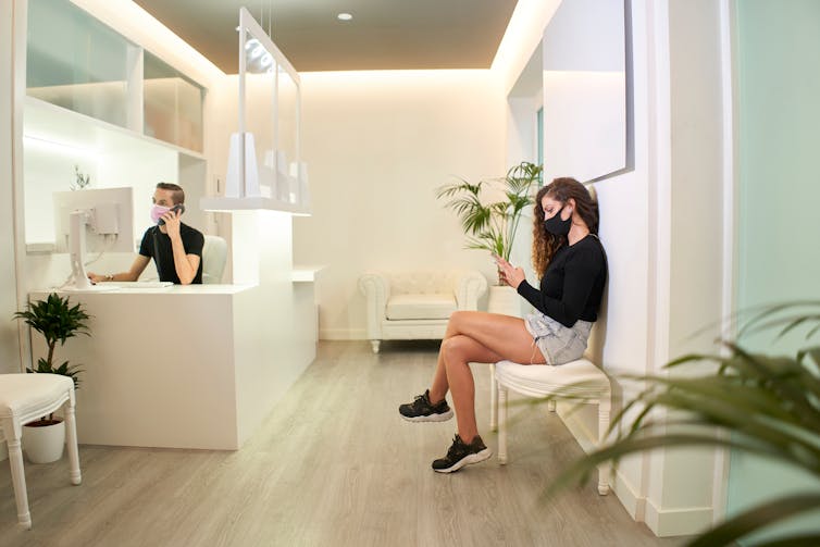 Woman in mask reads while in a medical waiting room