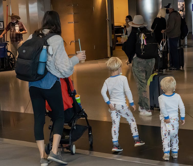two kids in airport scratching bottoms