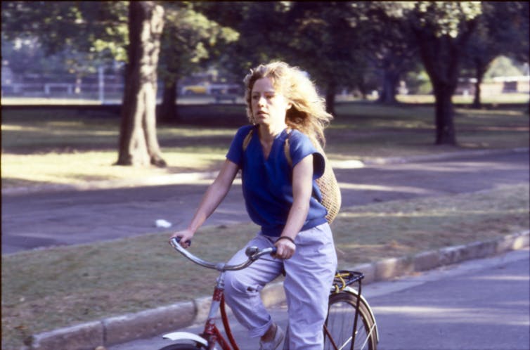 a woman riding a bike past the Edinburgh Gardens