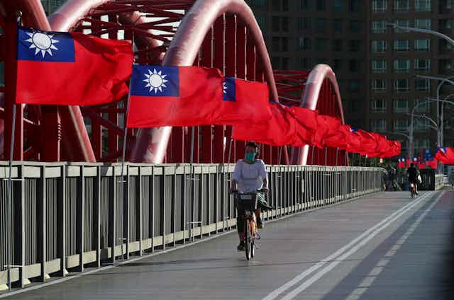 A cyclist rides past Taiwan national flags on a bridge in Taipei.