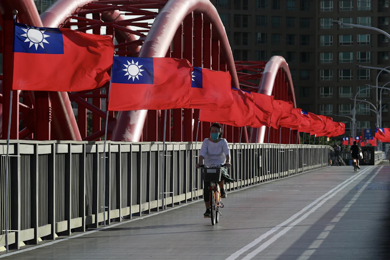 A cyclist rides past Taiwan national flags on a bridge in Taipei.