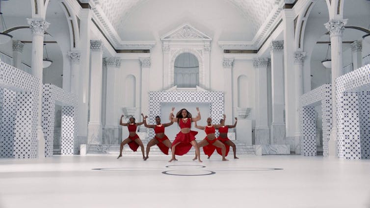 Un groupe de danseurs dans un décor blanc