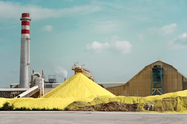 A pile of yellow sulfur outside a factory.
