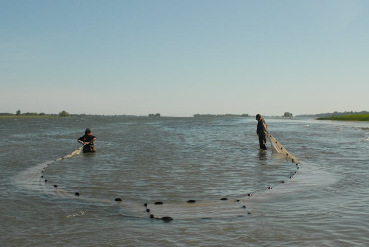 2 personen déploient un filet dans l'eau