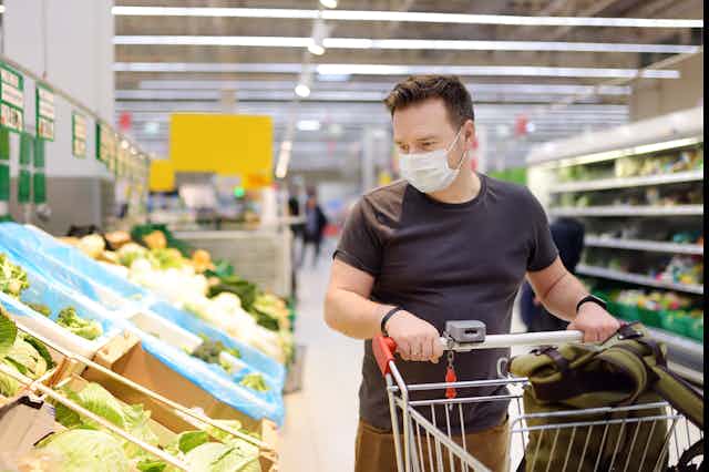 A man wearing a mask is shopping at the supermarket.
