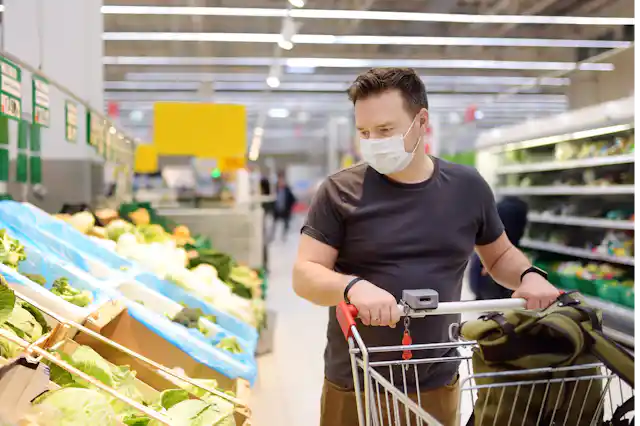 A man wearing a mask is shopping at the supermarket.