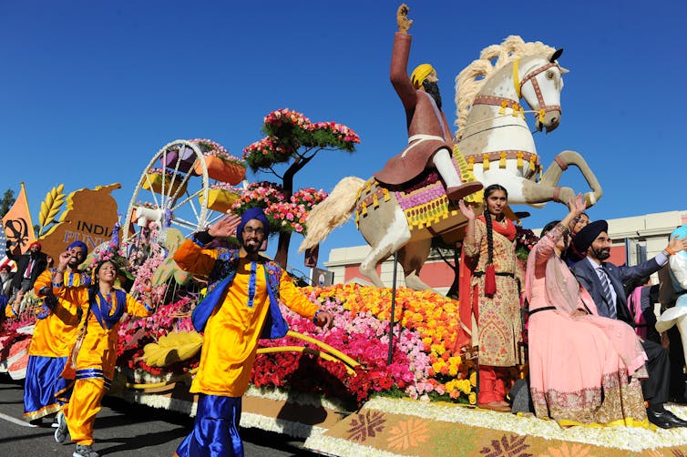 A colorful tableau with a horse and men and women in bright attire standing on it.