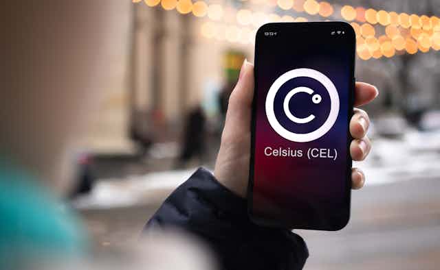 A hand holding a cellphone with the crypto platform Celsius logo on the screen