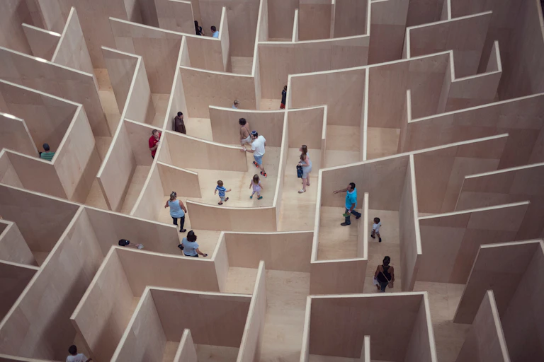 A shot from above of several people making their way through a life-size maze