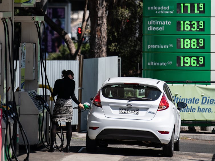 woman fills white car with petrol