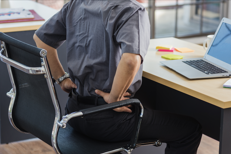 Woman in chair holding back