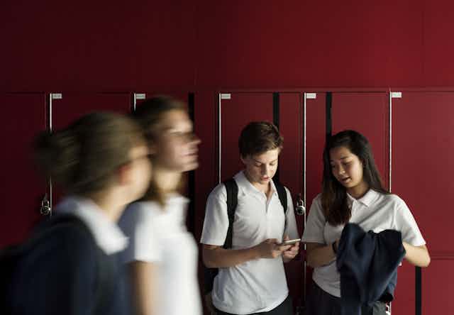 Students outside their lockers with a phone.