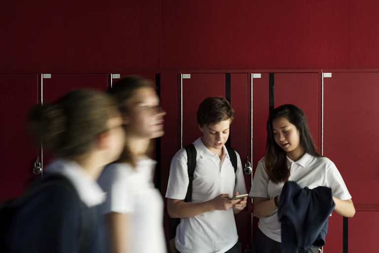 Students outside their lockers with a phone.