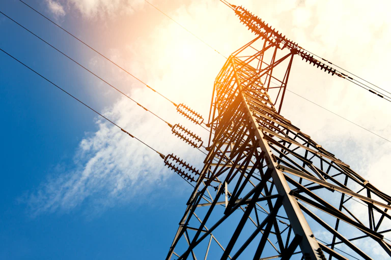 Electricity pylon against sunny sky with clouds