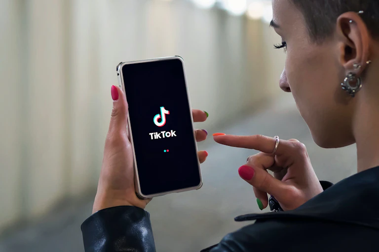 Joven con un móvil en la mano con el símbolo de TikTok.