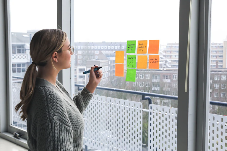 A woman marks post-its on a window
