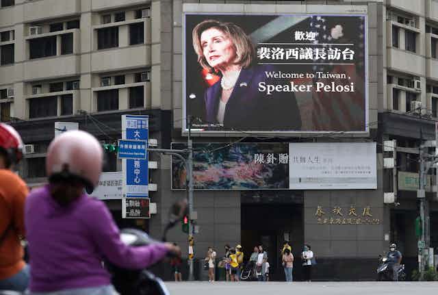 Un panneau d'affichage situé dans une rue passante affiche le visage de Nancy Pelosi et lui souhaite la bienvenue à Taïwan.